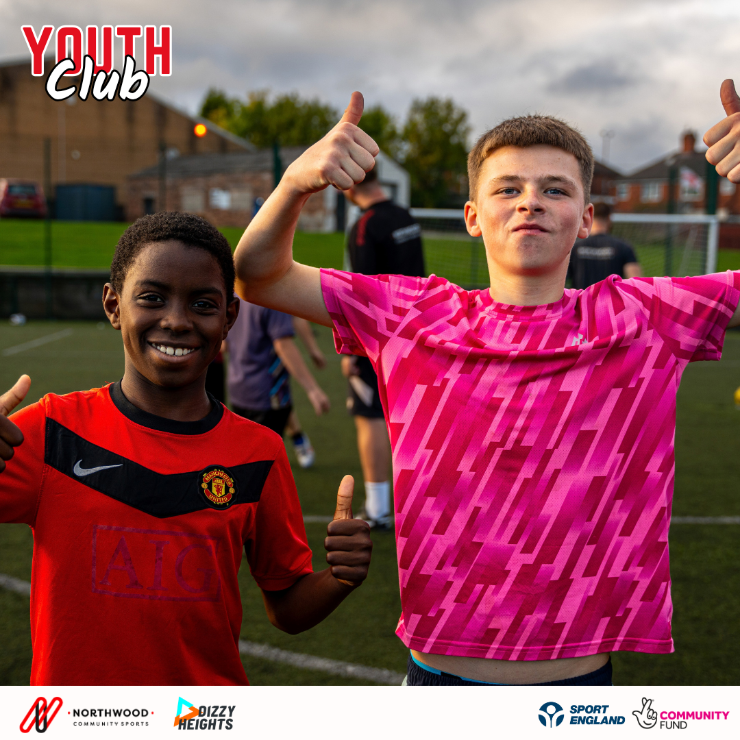 Two young people smiling and giving a thumbs up